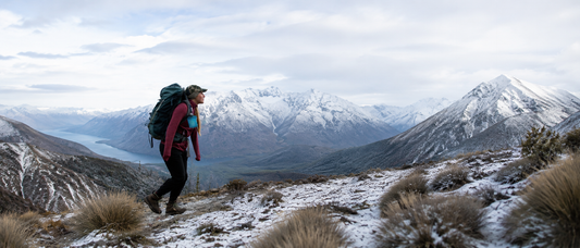 Female hiker carrying a large backpack through a snowy NZ alpine landscape in winter